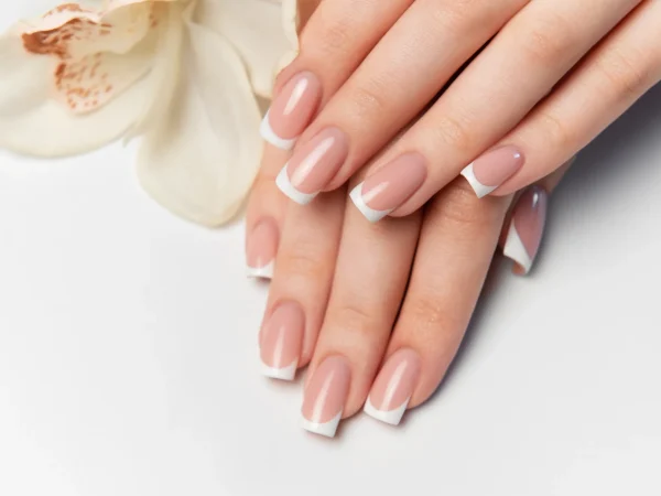 woman-showing-french-manicure-white-orchid-flower (1)_11_11zon